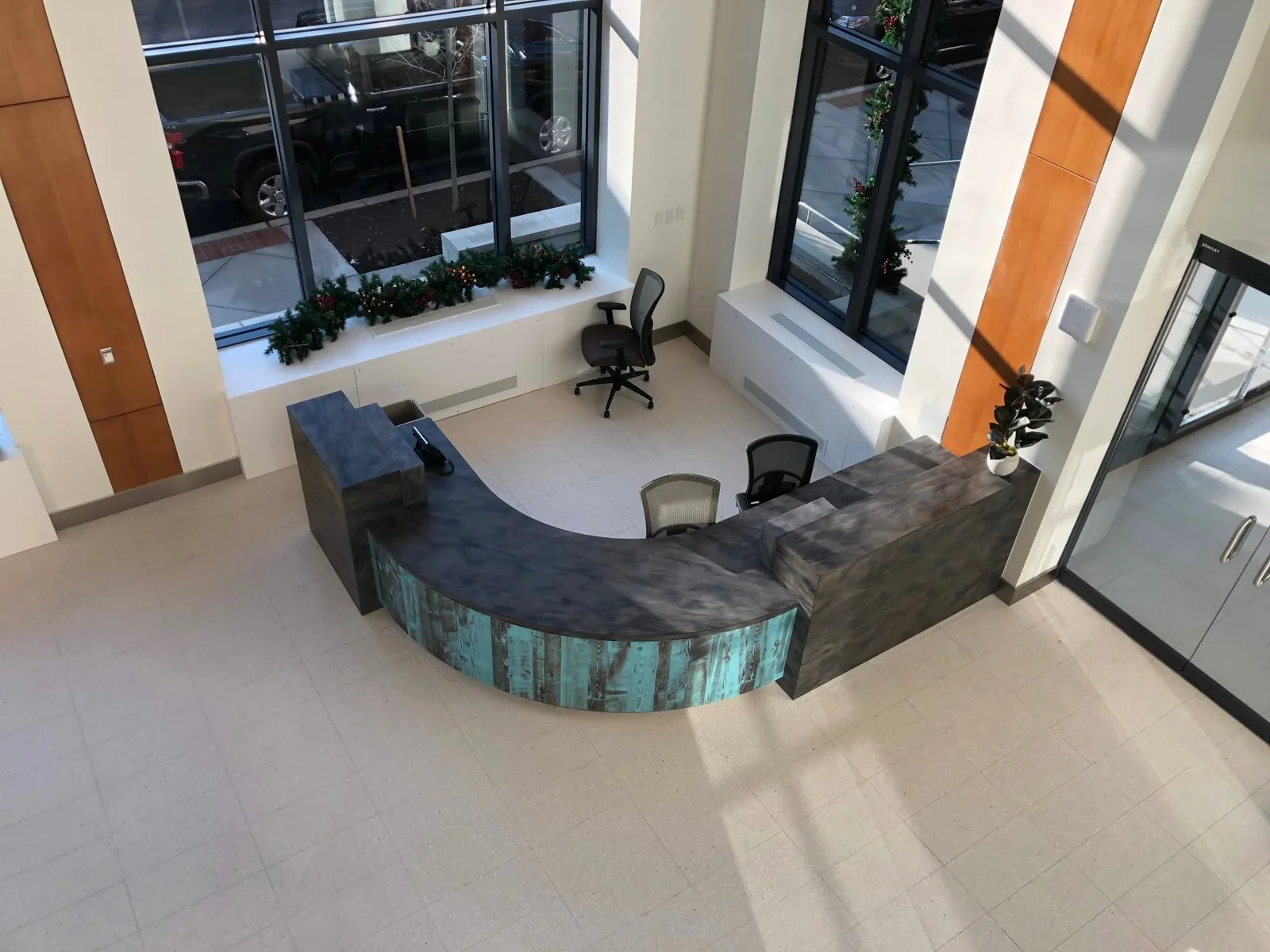 Overhead view of a curved reception desk with a dark countertop and turquoise-toned front panels.