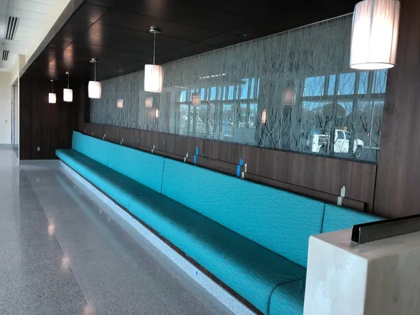 Long teal banquette beneath dark wood wall paneling at Beebe Rehoboth Health Campus.