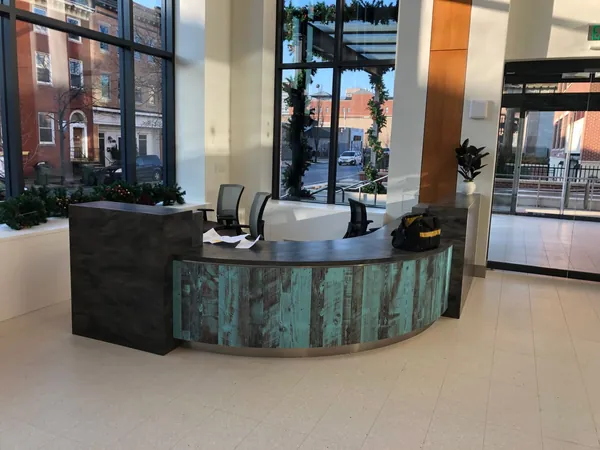 Curved reception desk with contrasting textured panels in the Helping Up Mission lobby.